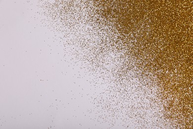 Shiny golden glitter on white background, top view