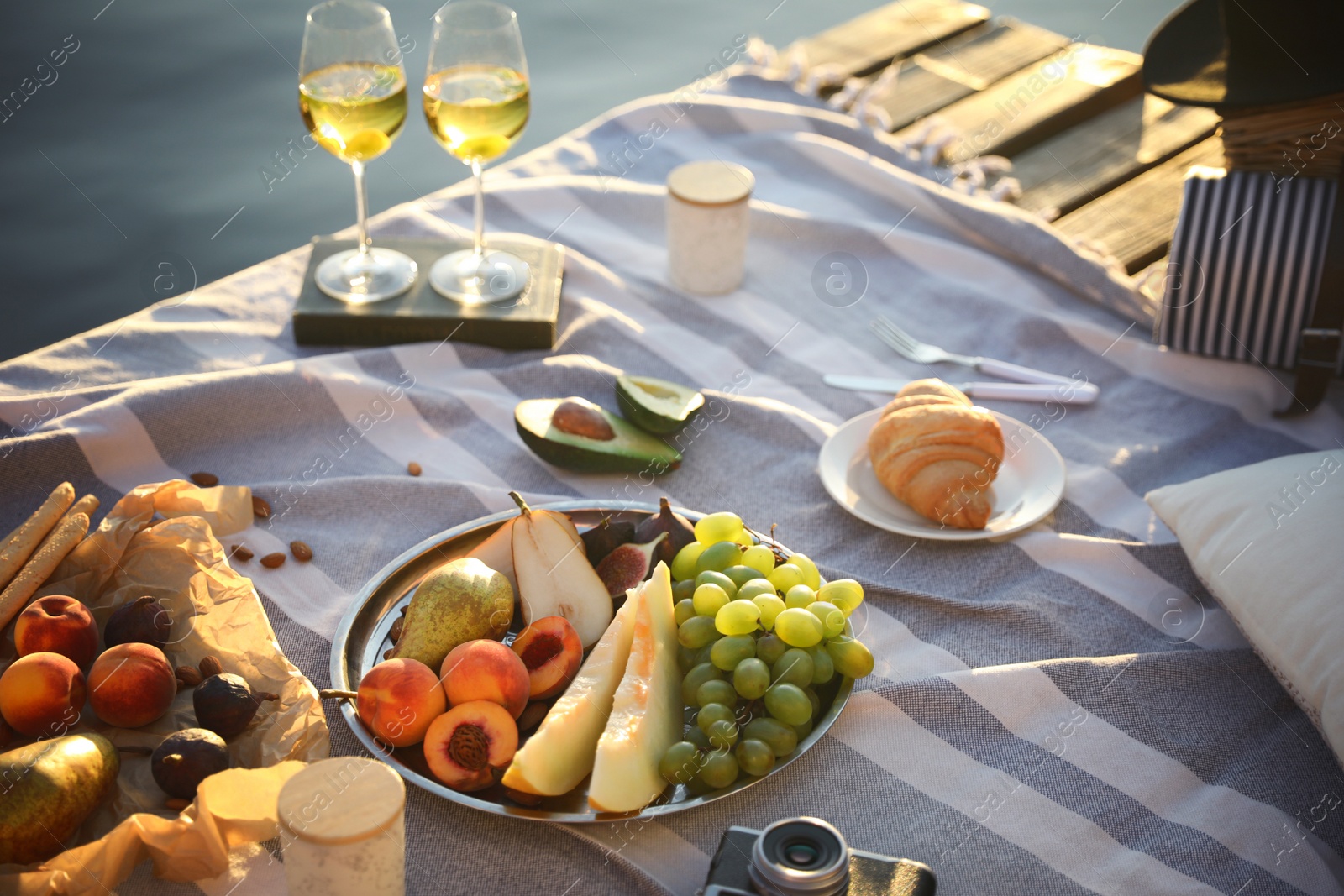 Photo of Picnic blanket with delicious food and wine on pier