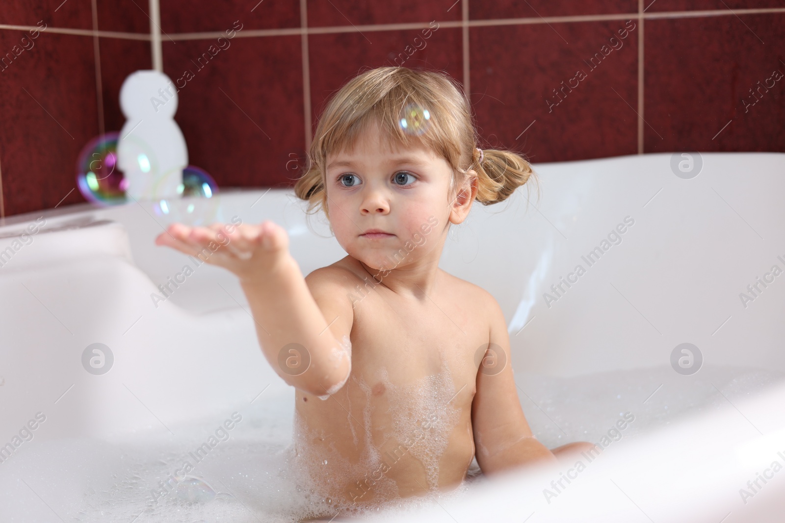 Photo of Little girl bathing in tub at home