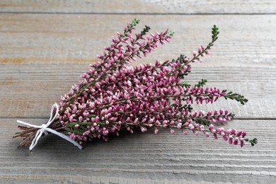 Photo of Bunch of heather branches with beautiful flowers on grey wooden table