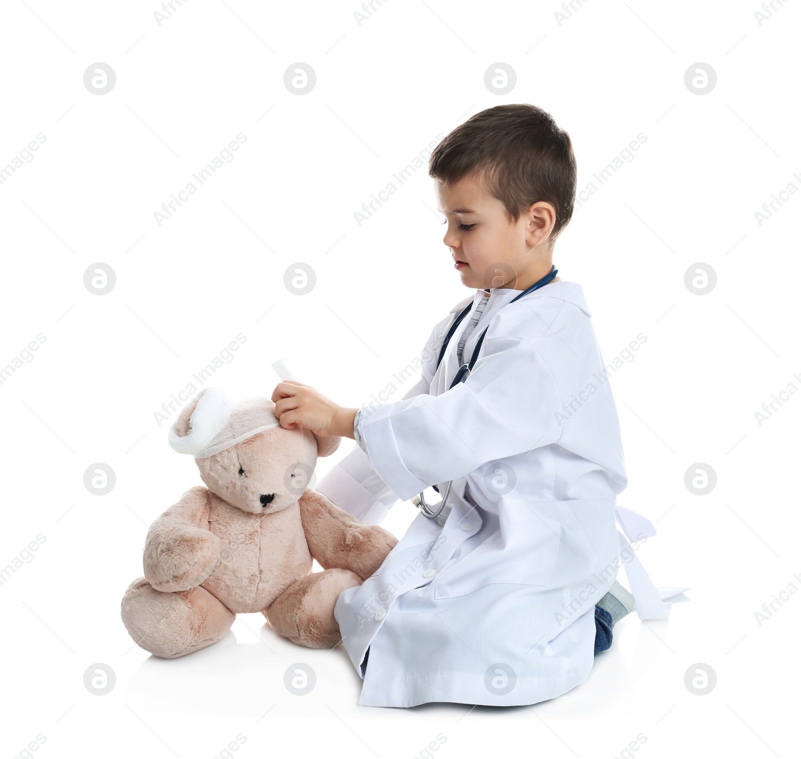 Photo of Cute child playing doctor with stuffed toy on white background