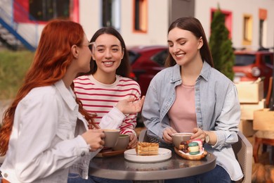 Photo of Happy friends talking and drinking coffee in outdoor cafe