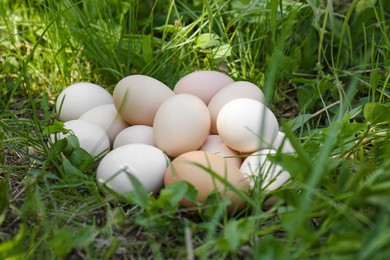 Photo of Pile of fresh raw eggs on green grass outdoors