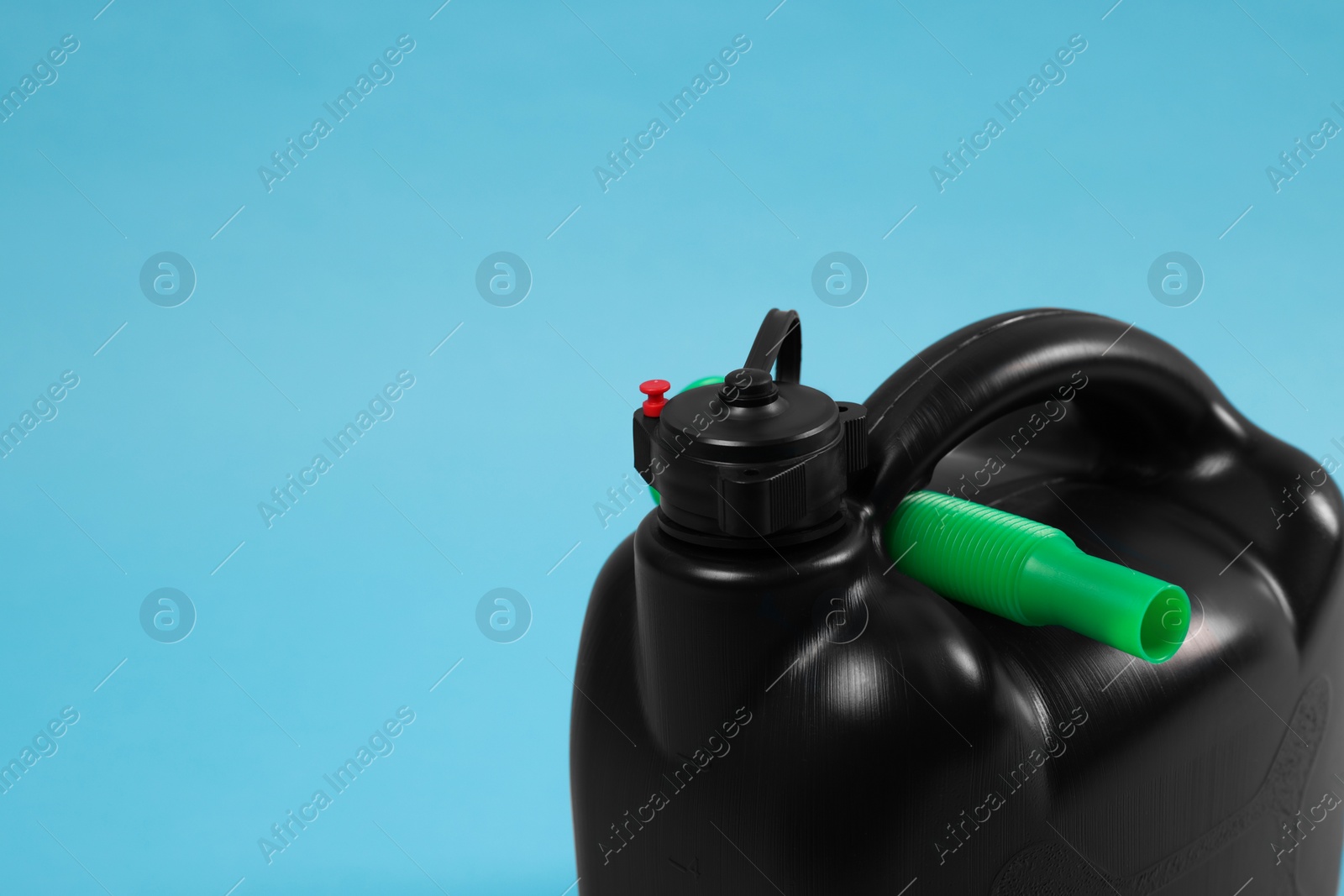 Photo of New black plastic canister on light blue background, closeup. Space for text