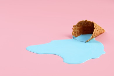 Photo of Melted ice cream and wafer cone on pink background. Space for text