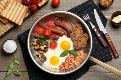 Traditional English breakfast with eggs served on wooden table, flat lay