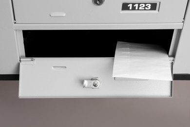 Open metal mailbox with envelope indoors, above view