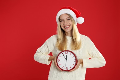 Photo of Woman in Santa hat with clock on red background. New Year countdown