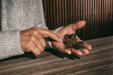 Photo of Poor senior woman with coins at table, closeup