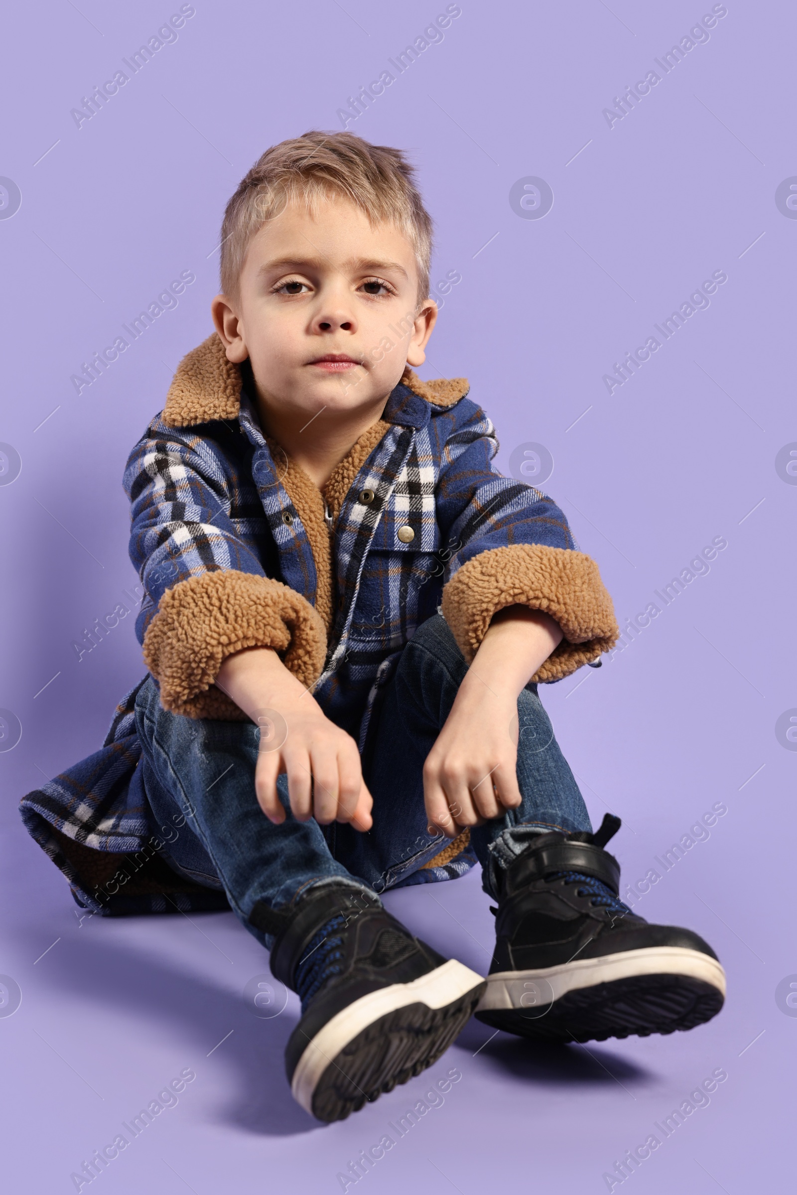 Photo of Fashion concept. Stylish boy posing on violet background