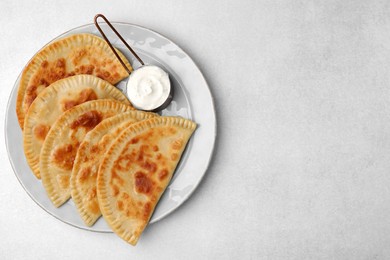 Photo of Delicious fried chebureki with cheese and sauce on light grey table, top view. Space for text