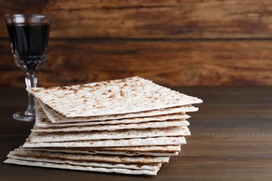 Photo of Stack of matzos and red wine on wooden table. Space for text