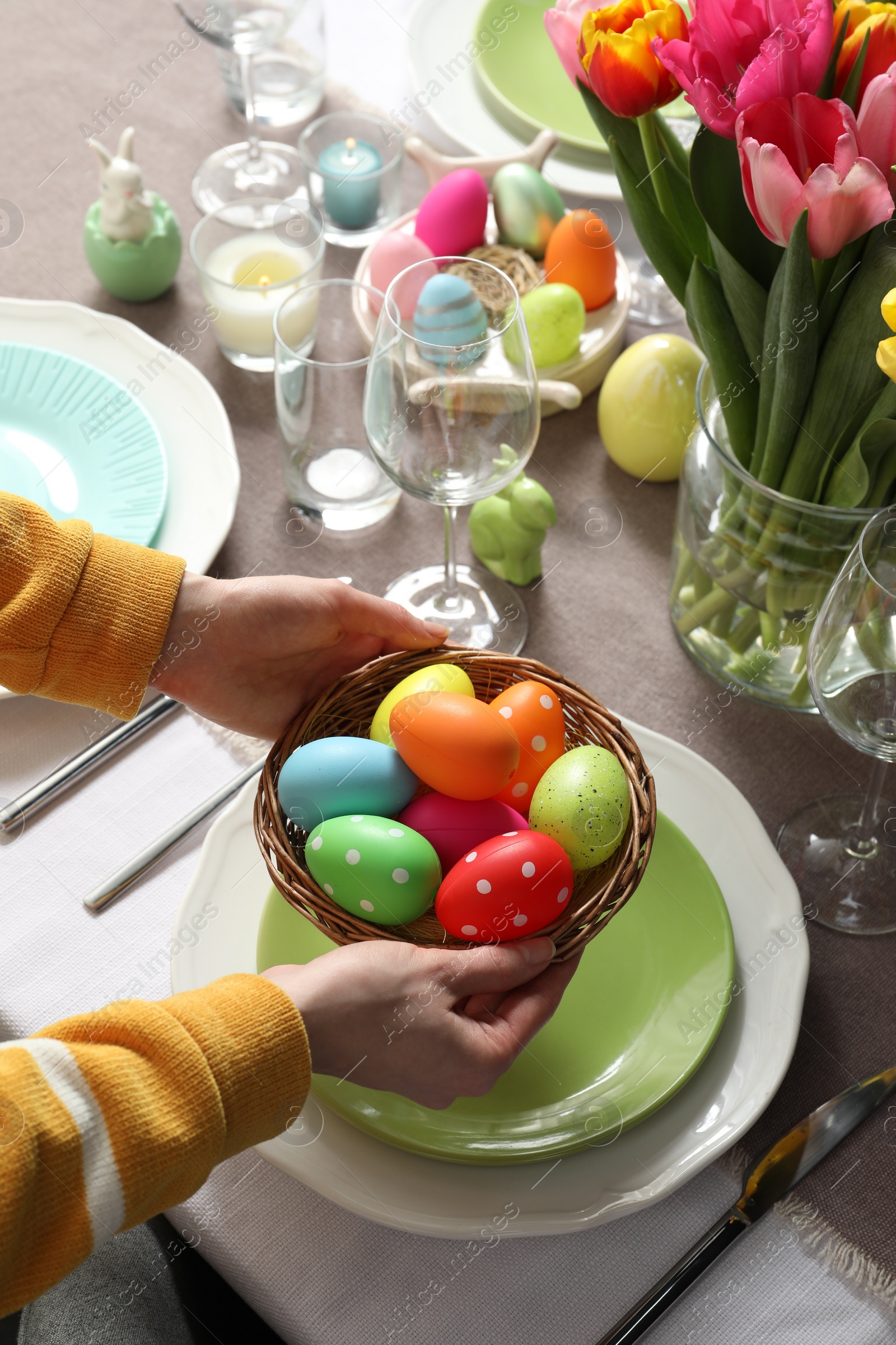 Photo of Woman setting table for festive Easter dinner at home, closeup