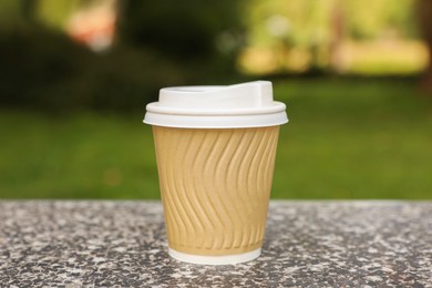 Photo of Paper cup on parapet in park, closeup. Coffee to go