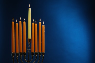 Hanukkah celebration. Menorah with burning candles on blue background, space for text