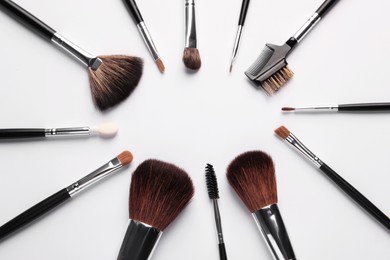 Photo of Frame of makeup brushes on white background, flat lay