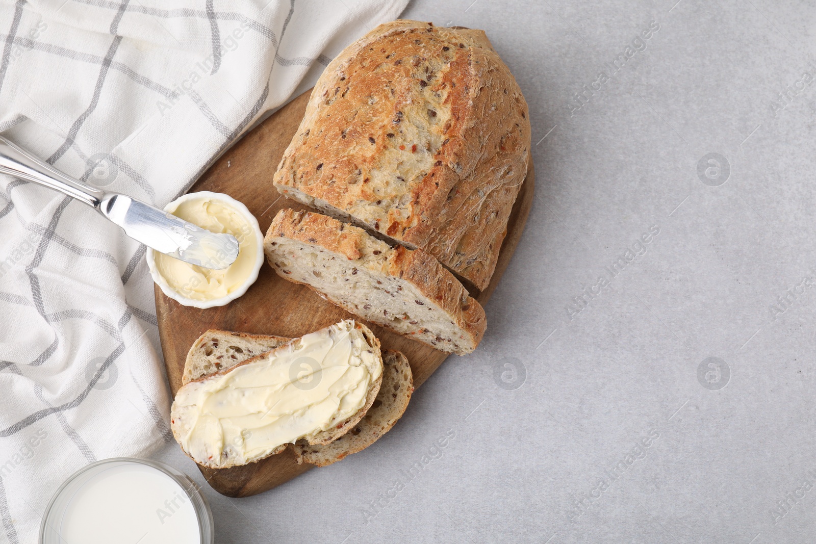 Photo of Tasty bread with butter, knife and milk in glass on gray table, flat lay. Space for text