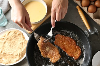 Photo of Woman cooking schnitzels in frying pan, top view