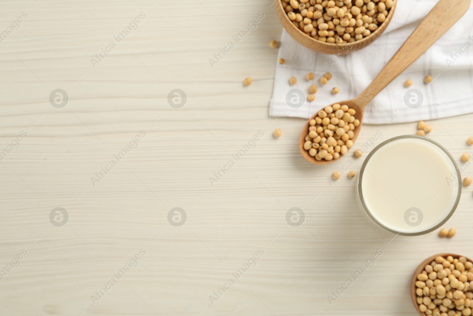 Photo of Soy milk and beans on wooden table, flat lay. Space for text