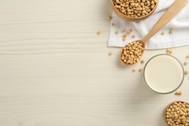 Soy milk and beans on wooden table, flat lay. Space for text