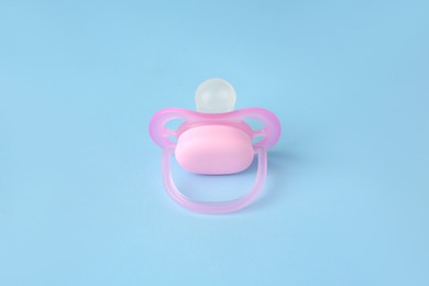 One new baby pacifier on light blue background