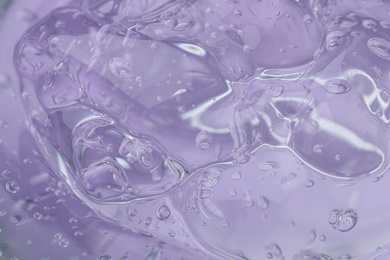 Photo of Pure transparent cosmetic gel on lilac background, closeup