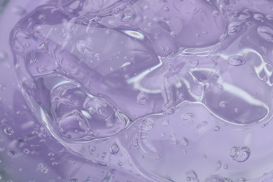 Pure transparent cosmetic gel on lilac background, closeup