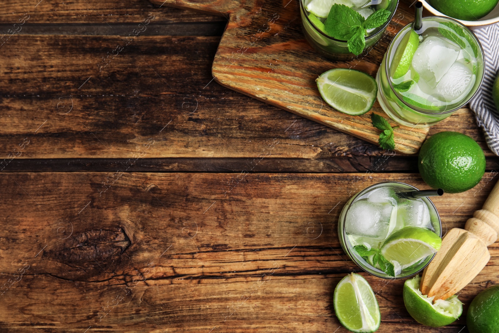 Photo of Delicious mojito and ingredients on wooden table, flat lay. Space for text