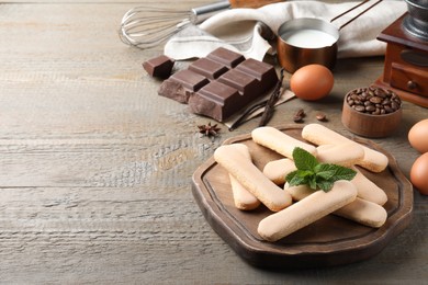 Tasty cookies and other tiramisu ingredients on wooden table, space for text