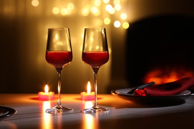 Photo of Glasses of wine and candles on table against blurred lights. Romantic dinner