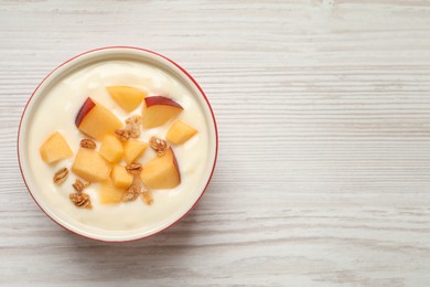 Photo of Delicious yogurt with fresh peach and granola on white wooden table, top view. Space for text