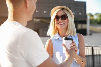 Photo of Happy couple with drink walking along city street on summer day