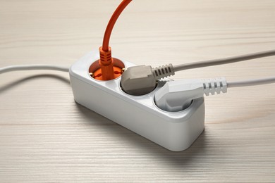 Photo of Extension cord with electrical plugs on white wooden floor. Electrician's equipment