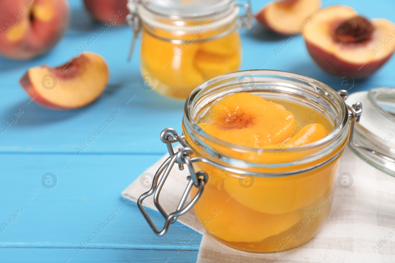 Photo of Glass jar with conserved peach halves on wooden table. Space for text