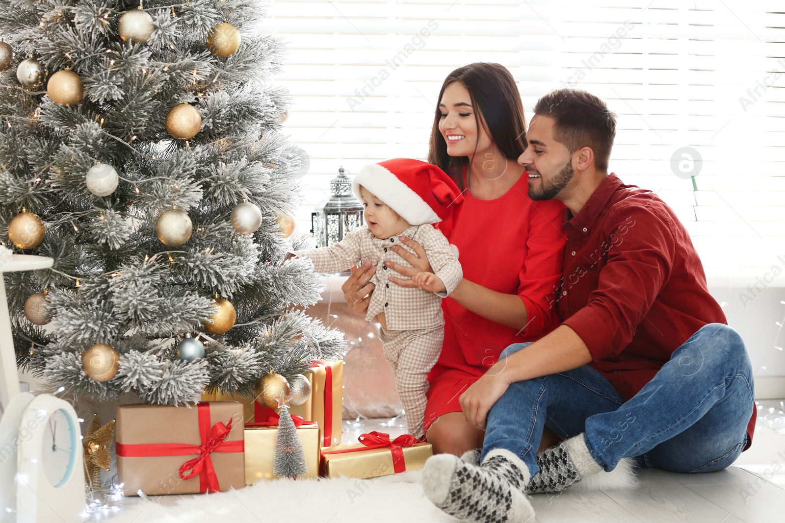 Photo of Happy family with cute baby near Christmas tree at home
