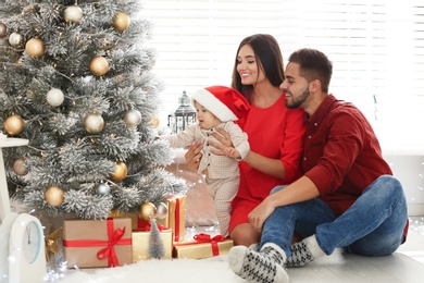 Happy family with cute baby near Christmas tree at home