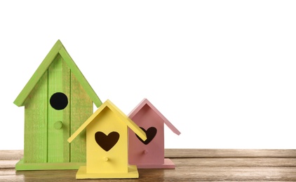 Three different bird houses on wooden table against white background