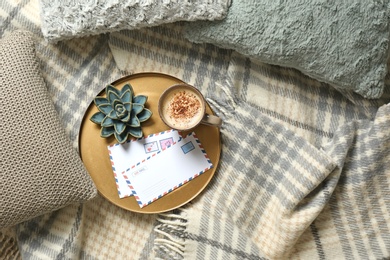 Photo of Pillows, plaid, tray with cup of coffee and letters on bed, flat lay