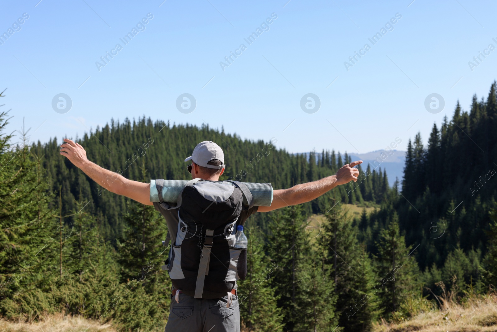 Photo of Tourist with backpack in mountains on sunny day, back view