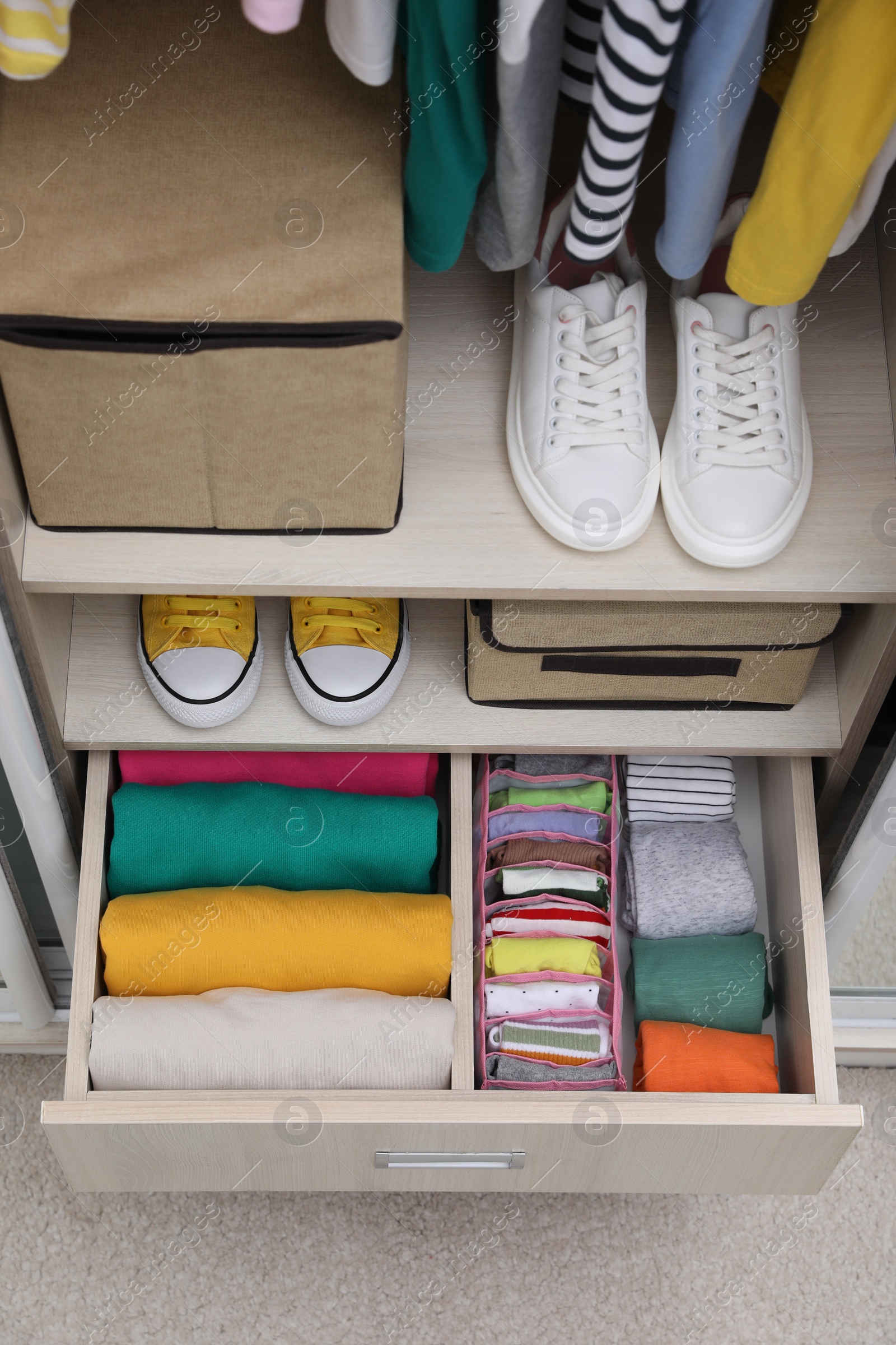 Photo of Wardrobe with organized clothes and shoes indoors, above view. Vertical storage