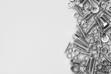 Photo of Different metal bolts and nuts on white background, flat lay. Space for text