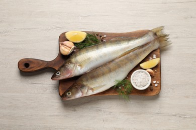 Photo of Fresh raw pike perches and ingredients on light wooden table, top view. River fish