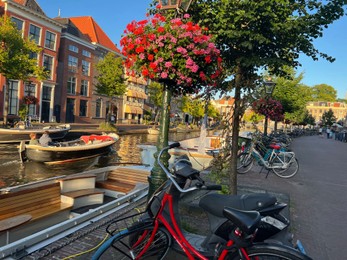 Leiden, Netherlands - August 1, 2022: Picturesque view of city canal with moored boats and parked bicycles