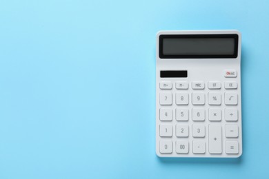 White calculator on light blue background, top view. Space for text