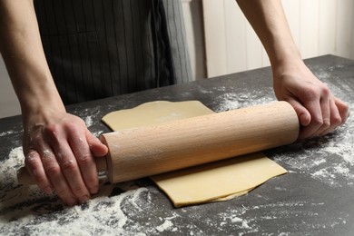 Photo of Woman rolling dough for pasta at grey table, closeup