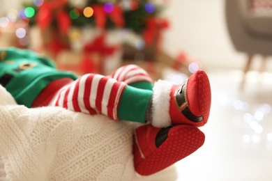 Photo of Cute baby in Christmas costume at home, focus on legs