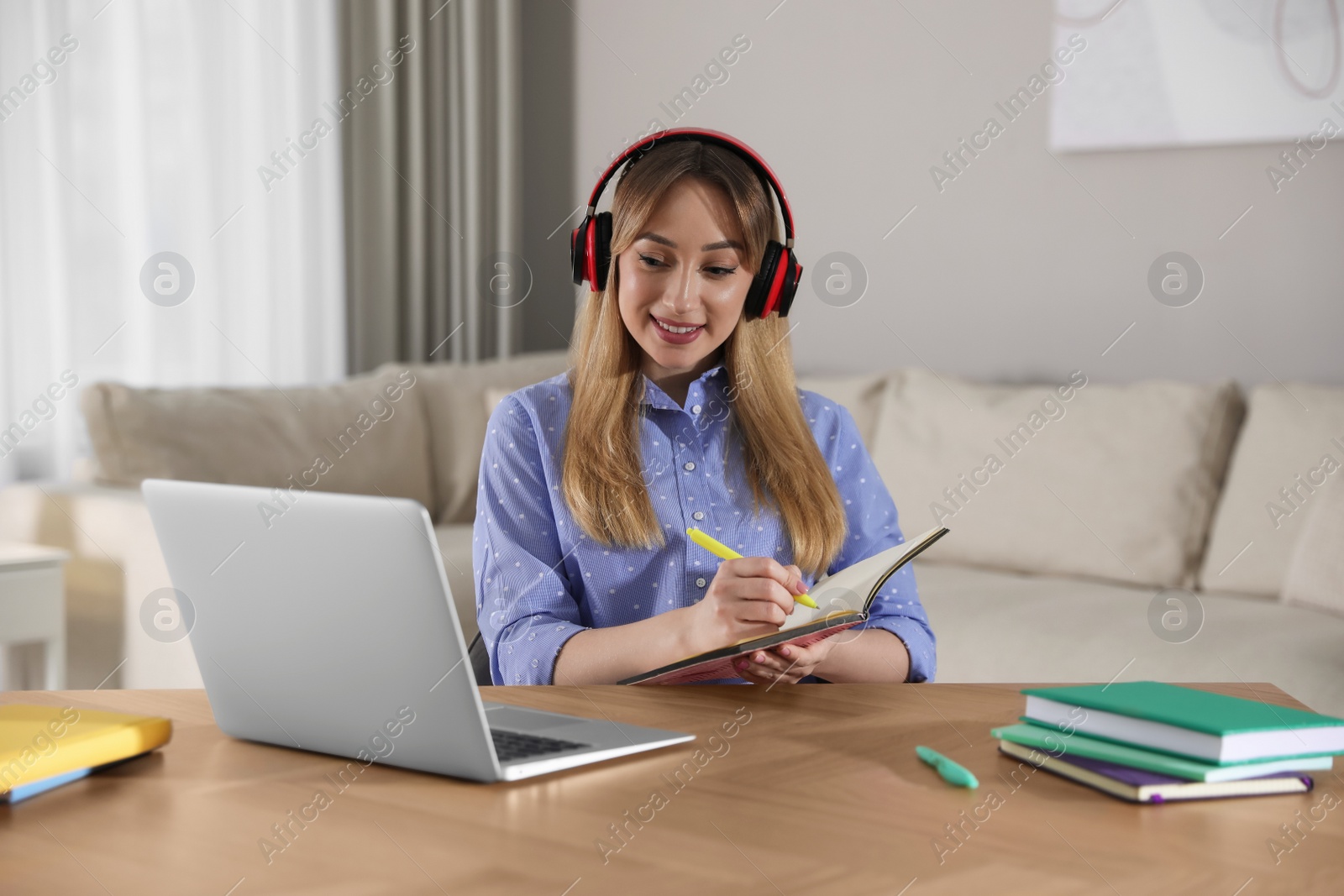 Photo of Young woman watching webinar at table in room