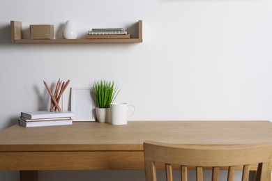 Photo of Comfortable workplace with wooden desk near white wall at home