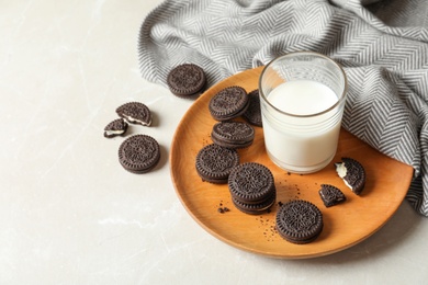 Photo of Plate with chocolate sandwich cookies and milk on table. Space for text