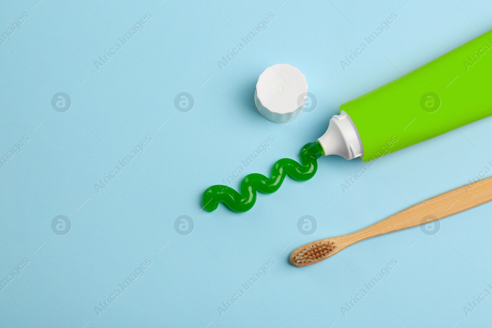 Photo of Tube of aloe toothpaste and toothbrush on light blue background, flat lay. Space for text